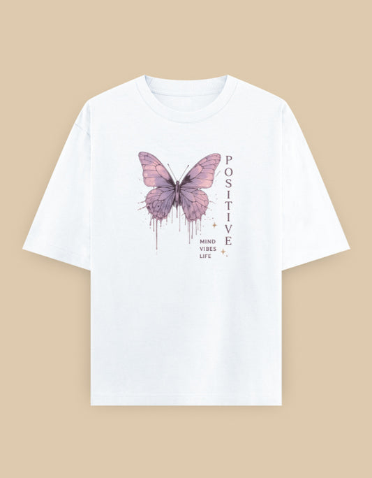 White oversized t-shirt featuring a pastel butterfly graphic with the inspirational message "Positive – Mind • Vibes • Life" printed on the front.