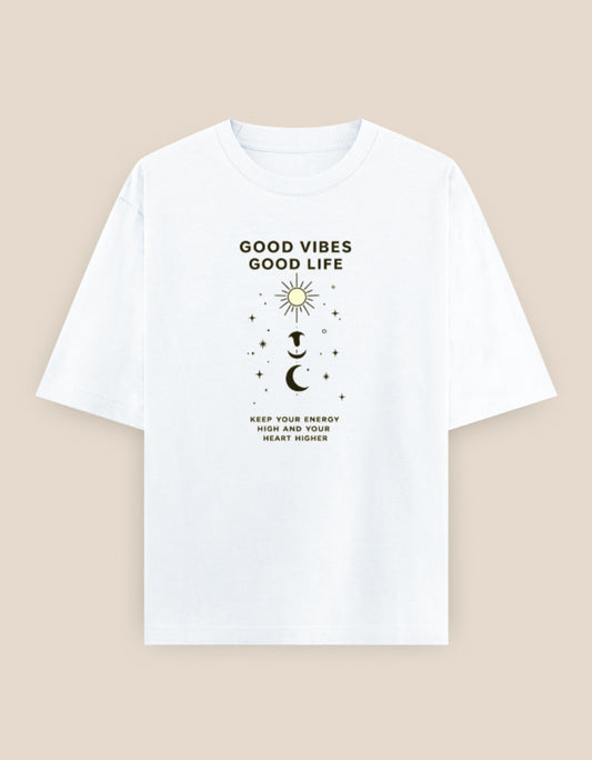 White oversized t-shirt featuring a minimalist "Good Vibes Good Life" graphic with celestial sun, moon, stars, and motivational typography on the front.
