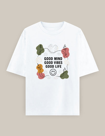 White oversized t-shirt featuring the inspirational quote "Good Mind Good Vibes Good Life" surrounded by minimalist botanical artwork and a smiley icon.