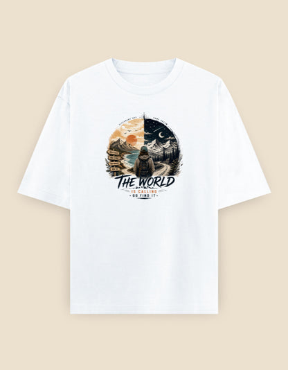 White oversized t-shirt featuring an adventure-inspired traveler illustration with a split day-and-night landscape and the quote "The World Is Calling – Go Find It" printed on the front.