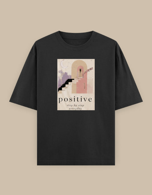 Black oversized t-shirt featuring a minimalist staircase illustration with the motivational message "Positive – Step by Step Everyday" printed on the front.