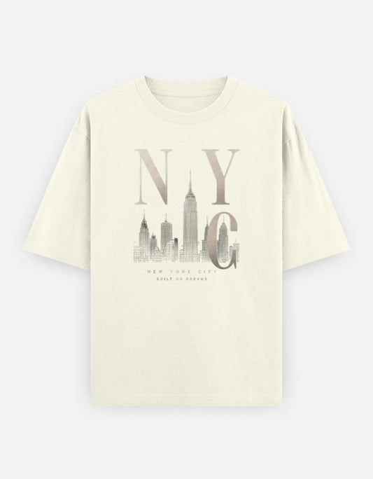 Off-white oversized t-shirt featuring a minimalist New York City skyline illustration with bold NYC typography printed on the front.